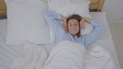 Happy-beautiful-woman-wake-up-smiling-and-stretching-her-arms-in-her-bed-in-the-bedroom.-Young-female-use-relax-time-at-home.-Lifestyle-woman-at-home-concept.